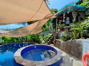 a swimming pool in a yard with a umbrella at Tanaw sa Anilao Beach Resort in Mabini