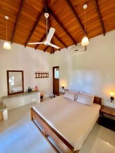 a bedroom with a large bed and a ceiling fan at Mansala Safari House in Udawalawe