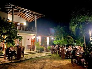 a group of people sitting at tables at a restaurant at night at Mansala Safari House in Udawalawe