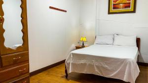 a bedroom with a bed and a dresser with a lamp at Apartamento El Roble in Iquitos