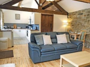 a living room with a blue couch and a kitchen at The Old Cow Shed in Barlow