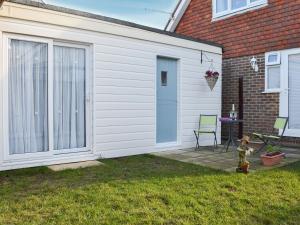 eine weiße Garage mit einer Tür neben einem Haus in der Unterkunft The Cabin in Pevensey