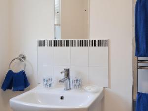 um lavatório branco numa casa de banho com toalhas azuis em The Cabin em Pevensey