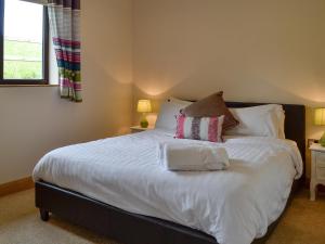 una camera da letto con letto, lenzuola e cuscini bianchi di River Cottage a Llangunllo