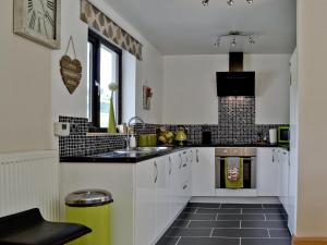 a kitchen with white cabinets and black tile floors at River Cottage in Llangunllo