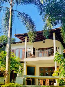 a house with a balcony and palm trees at Mansala Safari House in Udawalawe