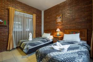 2 camas en una habitación con una pared de ladrillo en Sekararum Butik Syariah Guesthouse, en Bandung