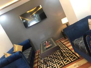 a living room with two blue couches and a tv at Lux Aparts Jhelum in Jhelum