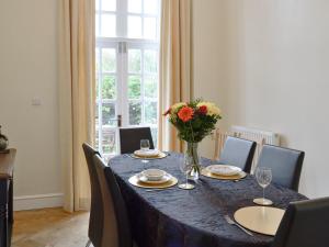 a dining room table with a vase of flowers on it at Yr Hen Fanc in Trawsfynydd