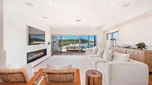 Una sala de estar con un sofá blanco y una chimenea. en Coast Fingal Bay, en Fingal Bay