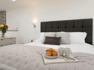 Una cama con una bandeja de cruasanes y un plato de pan. en The Retreat - Ukc3845 en Ticknall