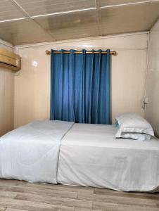 a large bed in a room with a blue curtain at Leaf Boat House in Miri