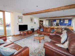 a living room with leather couches and a television at The Oaks in Ellesmere