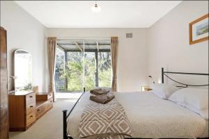 a bedroom with a bed and a large window at Mimosa Wines in Murrah