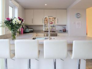 een keuken met witte kasten en een wastafel met witte stoelen bij Salty Dog in Findochty