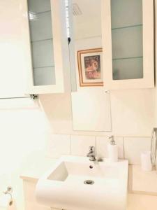 uma casa de banho branca com um lavatório e um espelho em Beach to Bush em Stanwell Park