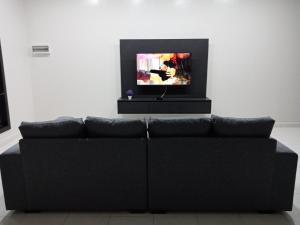 a black couch in a living room with a tv at 61 Homestay in Sitiawan
