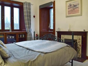 a bedroom with a bed and a fireplace and windows at The Gate House in Markinch