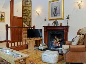 a living room with a fireplace and a tv at The Gate House in Markinch