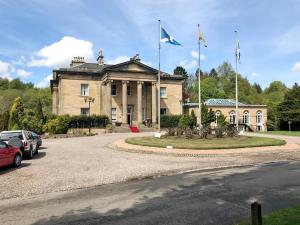 um edifício com duas bandeiras à frente em The Gate House em Markinch