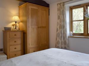 a bedroom with a bed and a dresser and a window at The Old Stables in Swerford