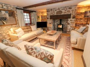 a living room with couches and a stone fireplace at Barn Cottage in Saint Erth