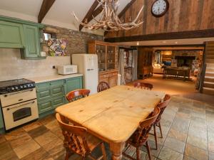a kitchen with green cabinets and a wooden table at Barn Cottage in Saint Erth