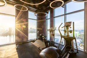 a gym with two exercise bikes in a room with windows at Wink Hotel Danang Riverside - 24hrs Stay & Rooftop with Sunset View in Danang