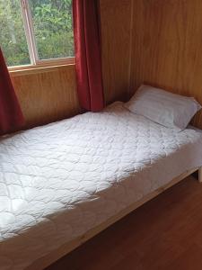 a bed in a small room with a window at Departamentos semiamoblado Puerto Montt in Puerto Montt