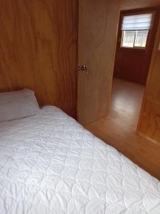 a bedroom with a white bed and a door at Departamentos semiamoblado Puerto Montt in Puerto Montt