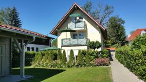 ein weißes Haus mit einem Balkon und einem Hof in der Unterkunft Ferienwohnung Ramsee in Herrsching am Ammersee