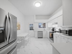 a white kitchen with a table and a refrigerator at Bloomfield/Shadyside @E Stylish and Modern Private Bedroom with Shared Bathroom in Pittsburgh