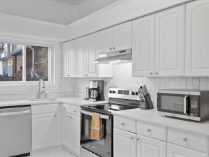 a kitchen with white cabinets and a stove top oven at Bloomfield/Shadyside @E Stylish and Modern Private Bedroom with Shared Bathroom in Pittsburgh