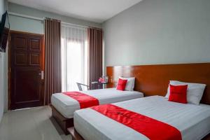 2 Betten in einem Hotelzimmer mit roten Kissen in der Unterkunft Reddoorz near Stadion Kridosono Blora in Blora