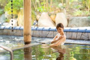 un bambino è seduto in piscina di Hotel Hoho "A hotel overlooking the Echigo Plain and the Yahiko mountain range" formerly Hotel Oohashi Yakata-no-Yu a Niigata
