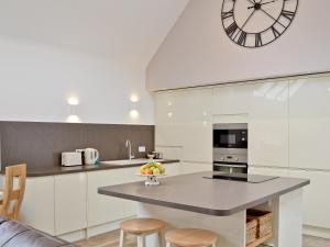 a kitchen with a table and a clock on the wall at Longcroft Dairy in Oyne