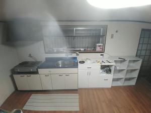 a small kitchen with white cabinets and a sink at 横城ゲストハウス in Kitsuki