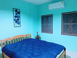 una camera da letto con pareti blu e un letto con un piumone blu di Nature home a Ban Laem Hin