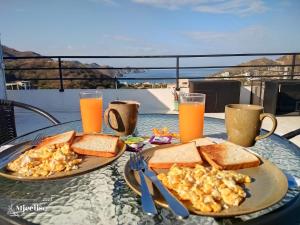 a table with two plates of food and orange juice at Samarian Hostel in Taganga