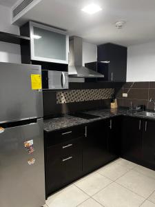 a kitchen with black cabinets and a stainless steel refrigerator at Cómoda suite en Puerto Santa Ana in Guayaquil