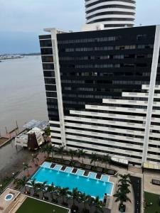 a large building with a swimming pool in front of it at Cómoda suite en Puerto Santa Ana in Guayaquil