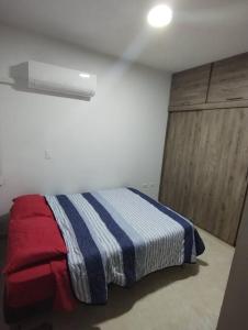 een slaapkamer met een bed met een gestreepte deken bij Apto amoblado al lado del Centro Comercial Jardín Plaza in Cúcuta