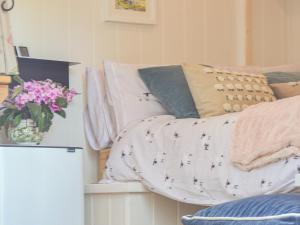 a bed with a blanket and a vase of flowers at Herdwick Hut in Twyn Llanan