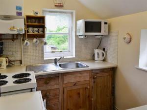 cocina con fregadero y microondas en Little Thatch en Netherbury