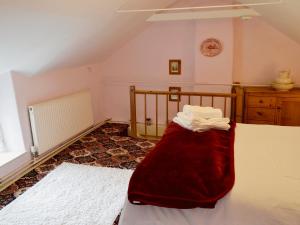 a bedroom with a bed with a red blanket on it at Little Thatch in Netherbury