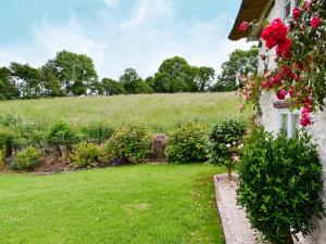 una casa con un patio verde con flores rosas en Little Thatch en Netherbury