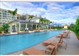 a large swimming pool with lounge chairs and a building at Ann's Condo "2bedroom" in Davao City