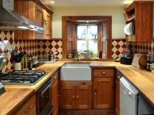 a kitchen with wooden cabinets and a sink and a window at Drumniall Cottage in Ordie