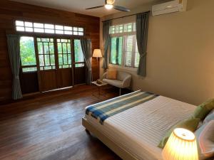 a bedroom with a bed and a chair and windows at Home of Dusita in Lamphun