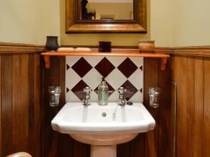 a bathroom with a white sink and a mirror at Drumniall Cottage in Ordie